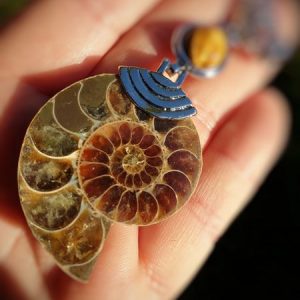 ammonite fossilisée ou opalisée montée en pendentif avec un oeil de tigre