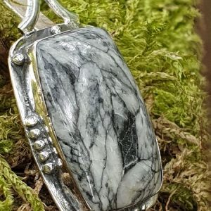 pendentif en pinolite suspendu à un arbre dans les bois, pierre naturelle noire et blanche