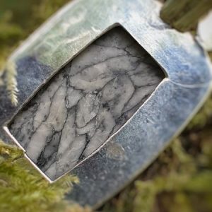 pendentif en pinolite suspendu à un arbre dans les bois, pierre naturelle noire et blanche