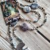 Long collier en merlinite ou opale dendrite, avec larimar. Photo avec carte du tarot l'ermite.